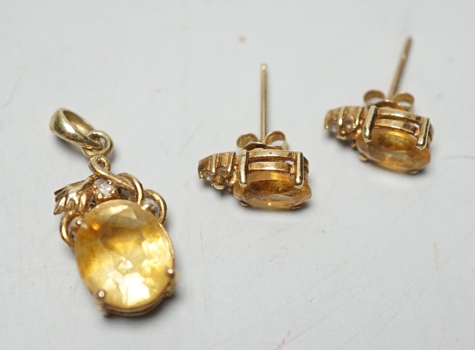 A modern 14k, citrine and diamond chip set pendant, 15mm and a pair of matching ear studs, gross weight 3.1 grams.